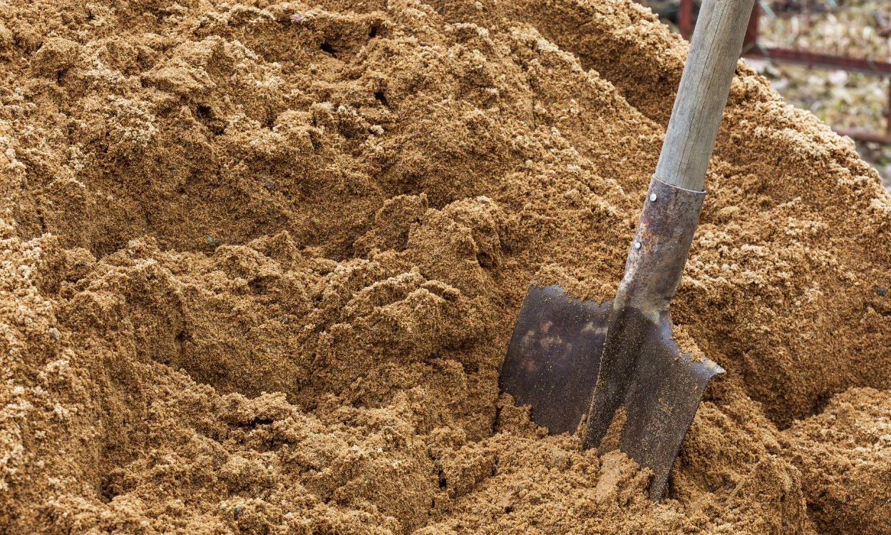 Building sand in a heap with a shovel