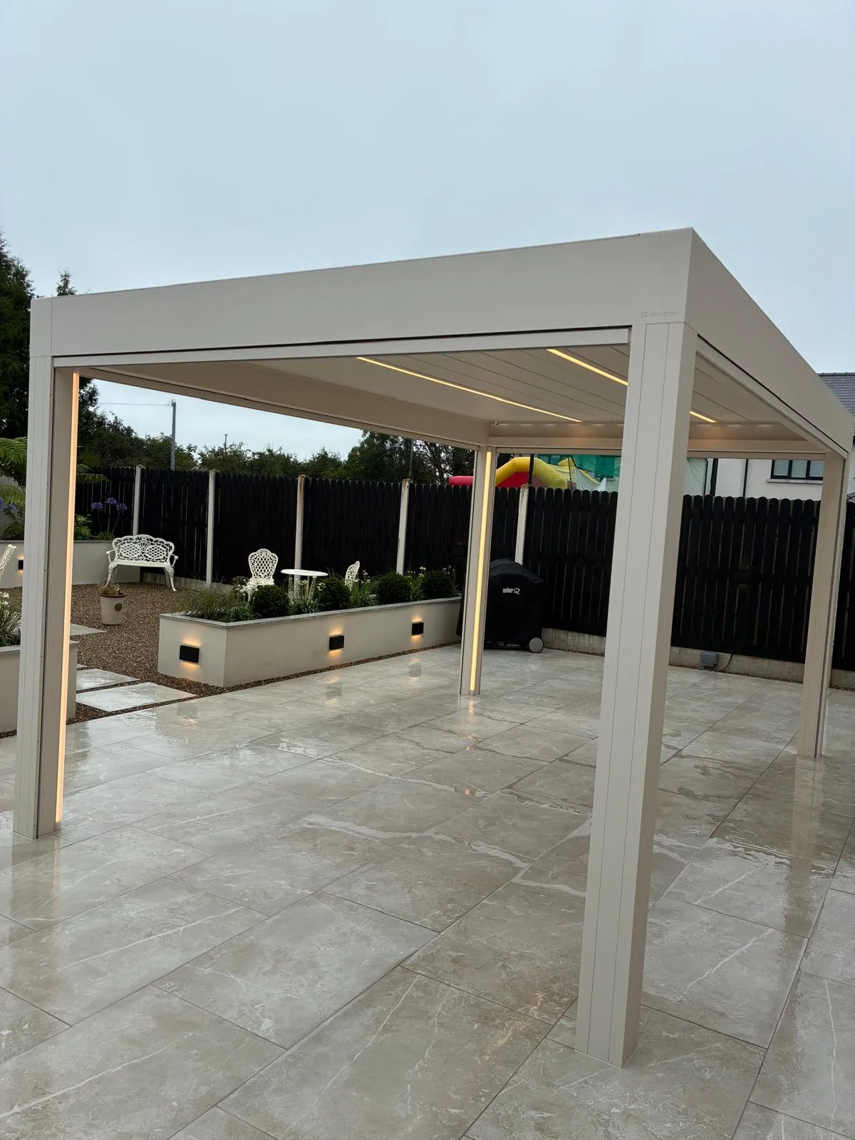 Pergola-covered patio with dining furniture and composite fencing