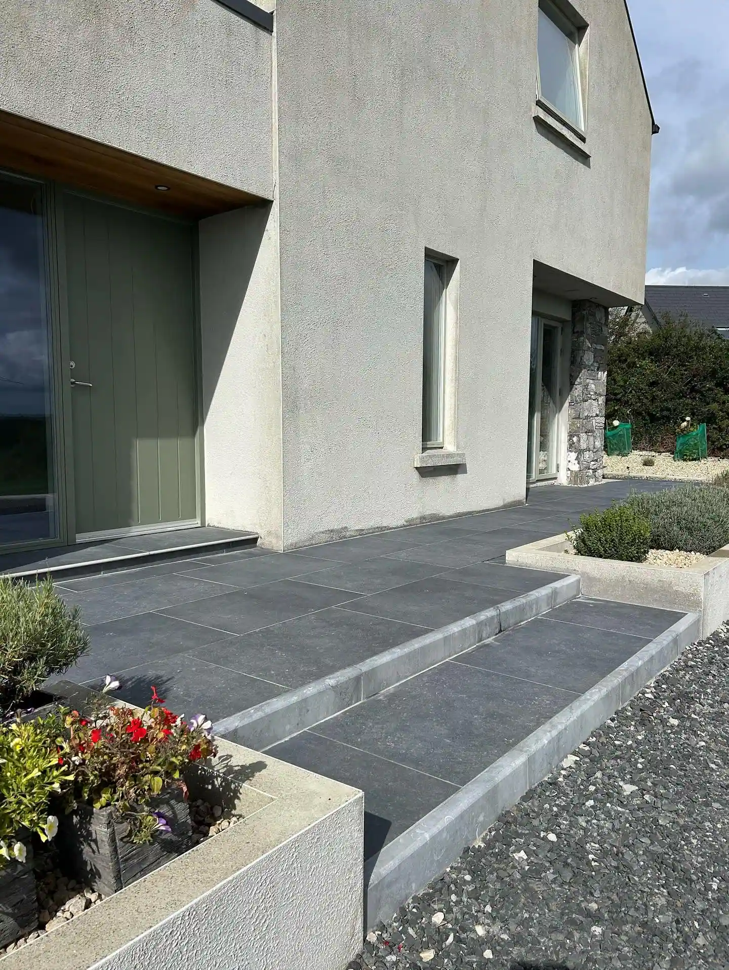 House entrance with a paved path, gravel border and stone-clad wall