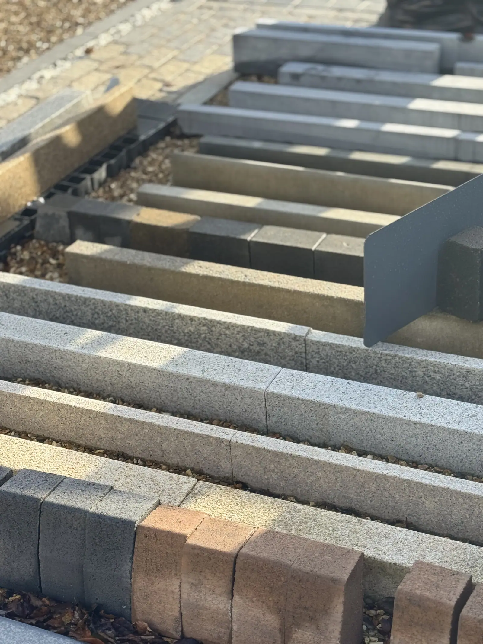 Kerbing and edging profiles laid out in rows beside a drainage channel
