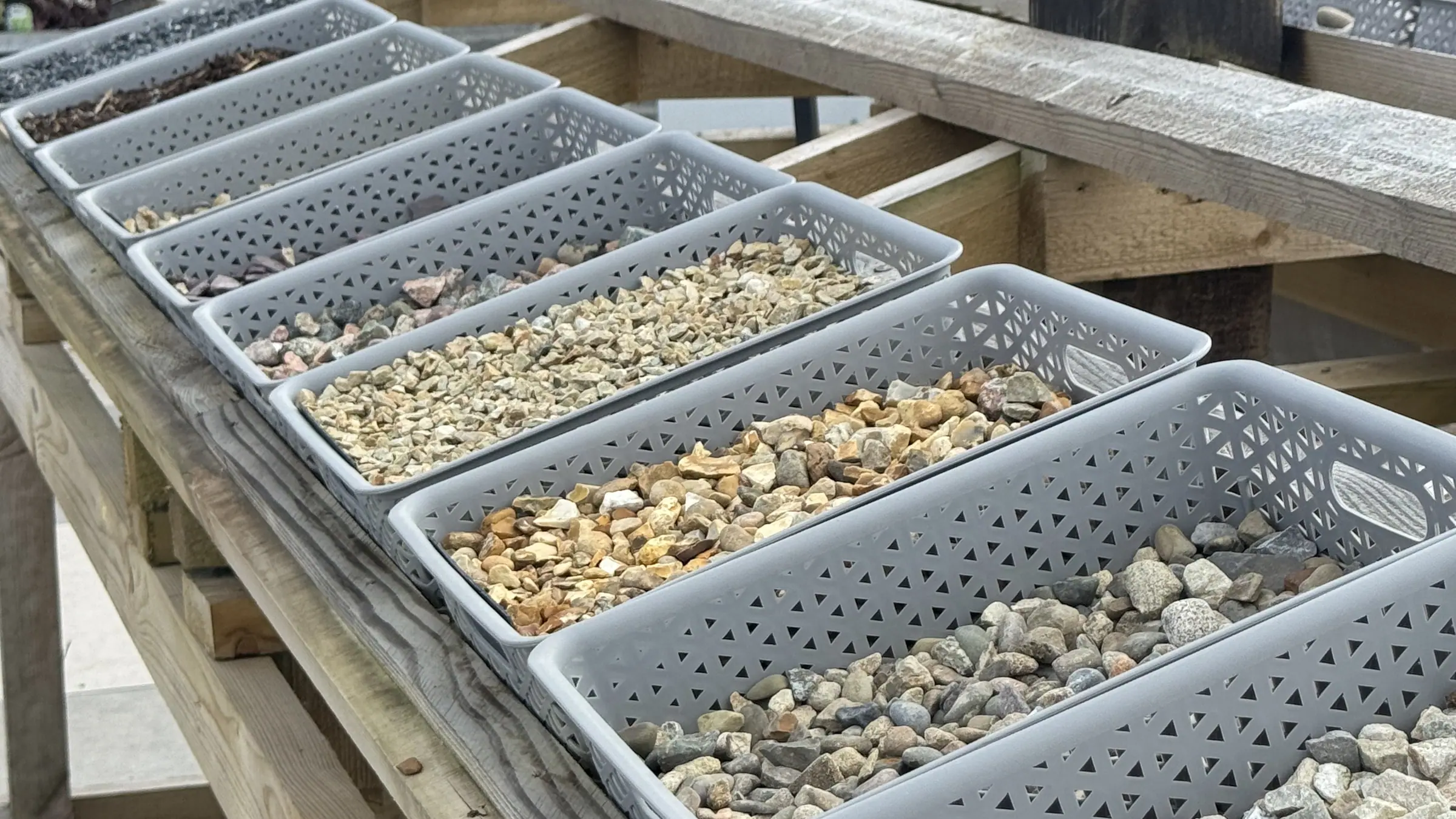 Trays of decorative stone samples lined up in the Creative Gardens yard