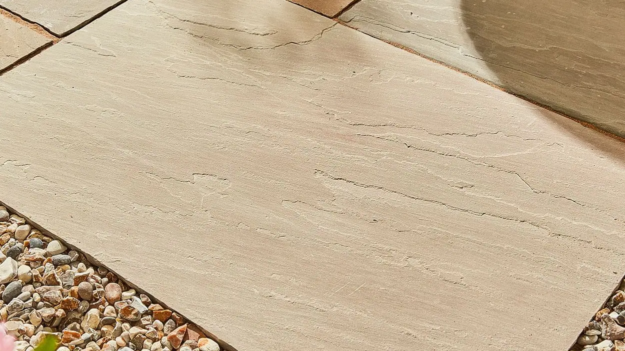 Natural sandstone paving laid on a patio, bordered by gravel