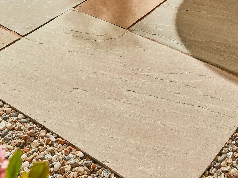 Natural sandstone paving laid on a patio, bordered by gravel