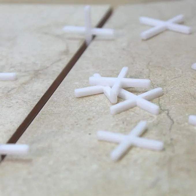 White plastic tile spacers set into a tile joint